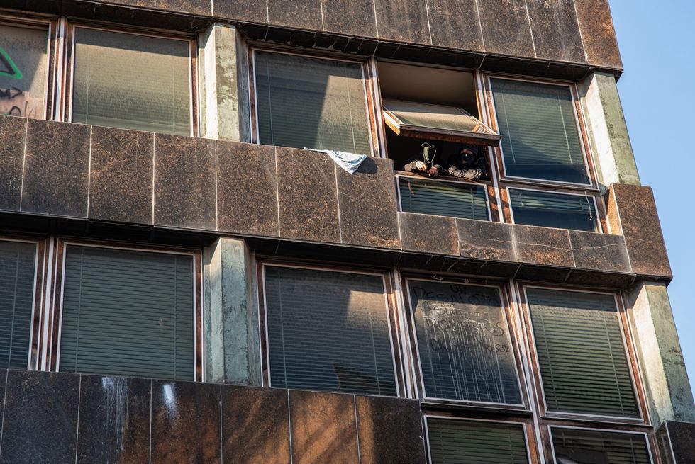 image showing Two men in an occupied building in Barcelona's ''La bonanova'' neighbourhood watch the anti-fascist rally in Barcelona.