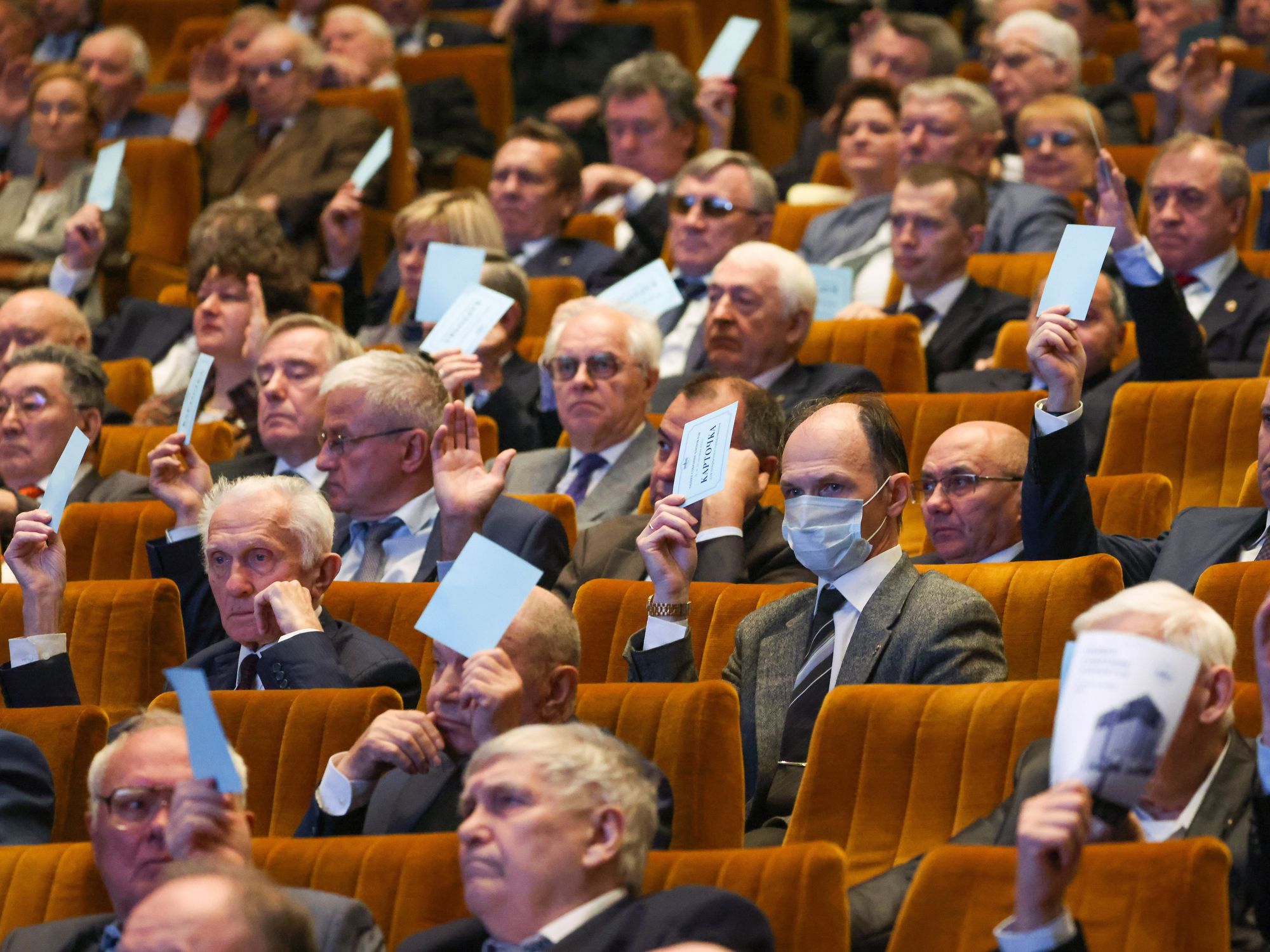 In an auditorium, members of the Russian Academy of Sciences raise papers to vote