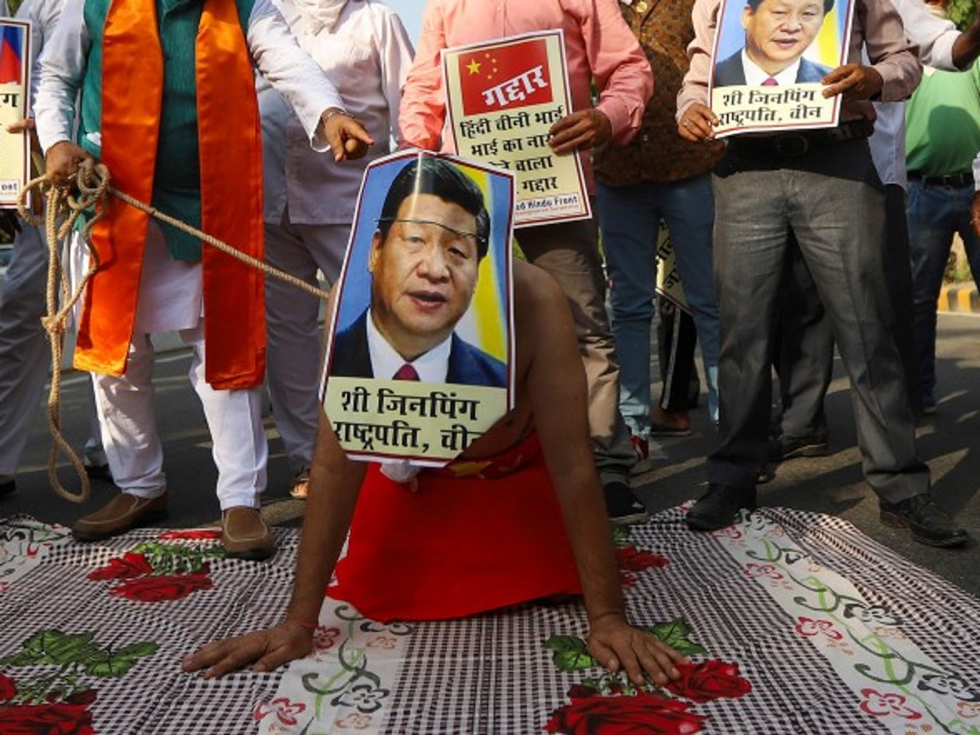 In Delhi, a protester covers his face with a poster of Chinese President Xi Jinping during an anti-China demonstration near the Chinese embassy.
