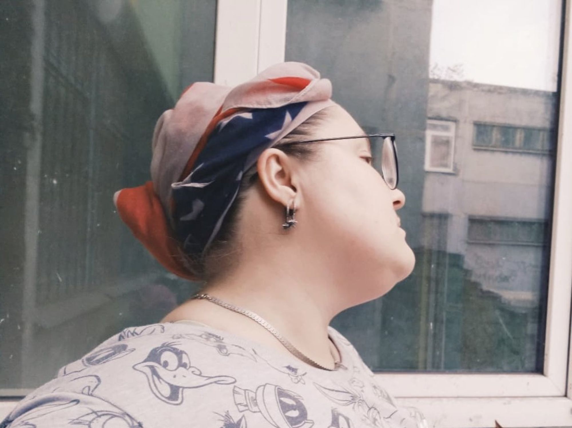 Inna, a woman in a headwrap and glasses, looks off camera