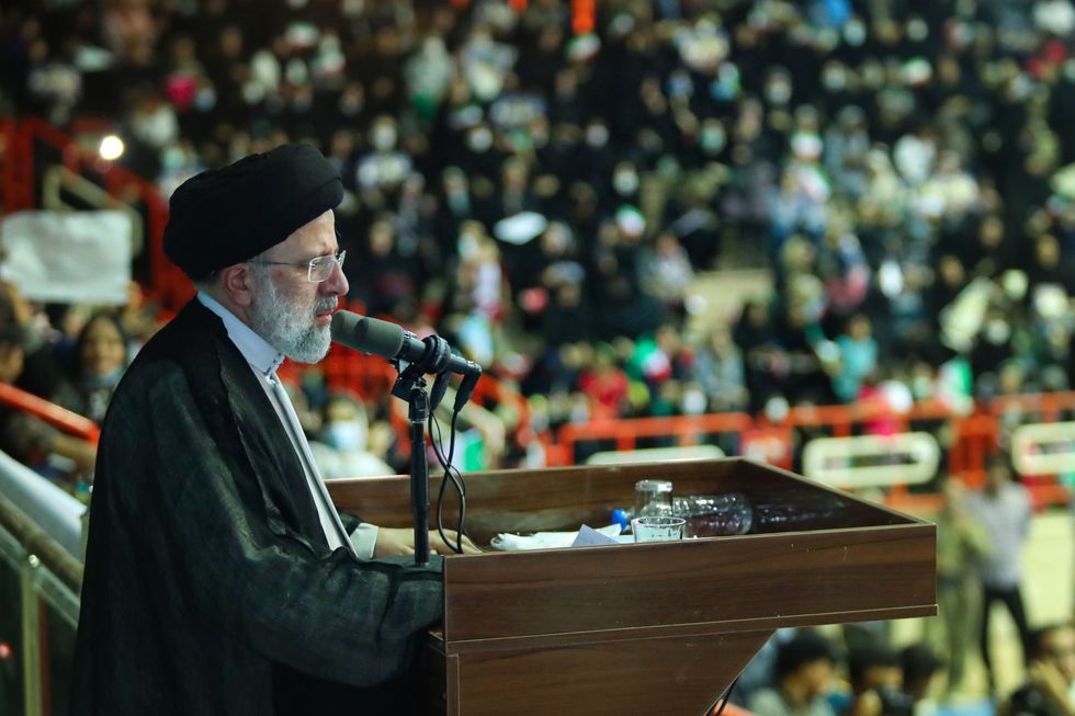Iranian President Ebrahim Raisi standing at a podium speaking to a crowd.