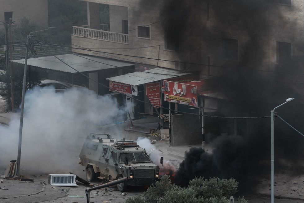Israeli forces in an armored vehicle clash with Palestinians in the occupied West Bank city of Jenin.