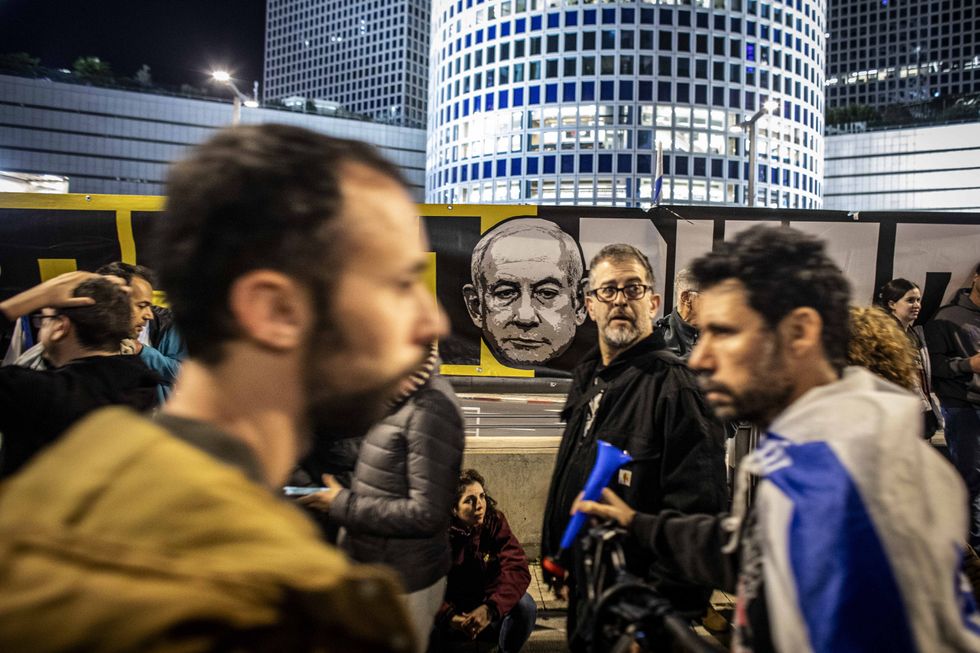 Israeli protesters walk past an anti-Netanyahu sign during a demonstration in Tel Aviv, Israel, on March 22, 2025.