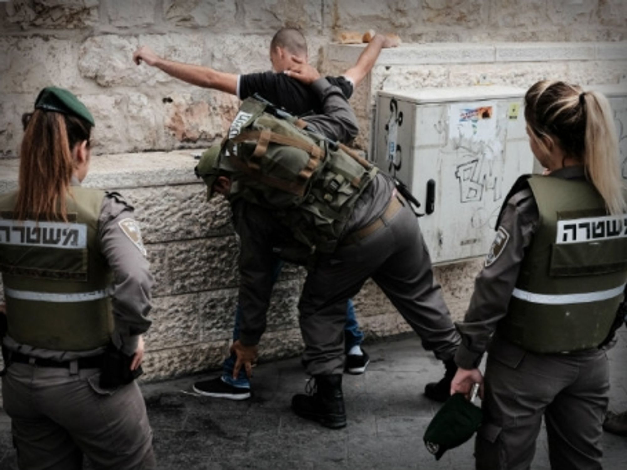 Israeli security forces search a Palestinian youth near the Jerusalem central bus station