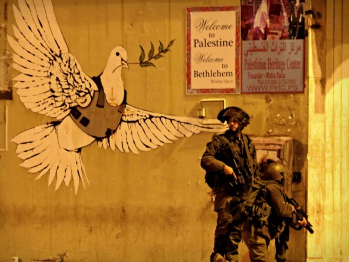 Israeli soldiers next to a Banksy mural in Bethlehem