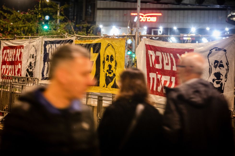 Israelis walk past anti-Netanyahu posters during a protest in Tel Aviv, calling Benjamin Netanyahu's government to reach a deal with Hamas for the release of the hostages.