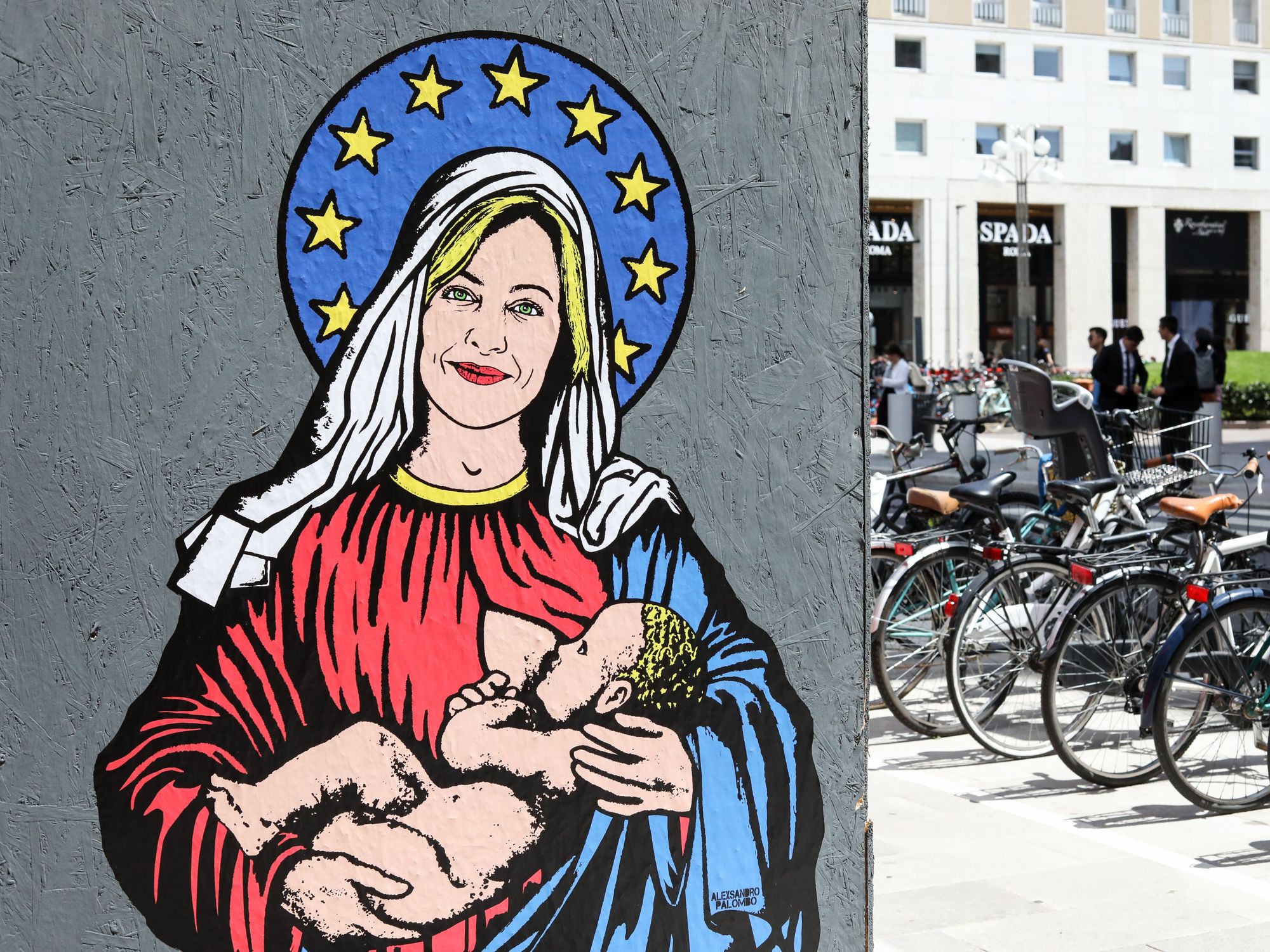 Italian Prime Minister Giorgia Meloni with European flag halo while holding a breastfeeding baby in her arms.