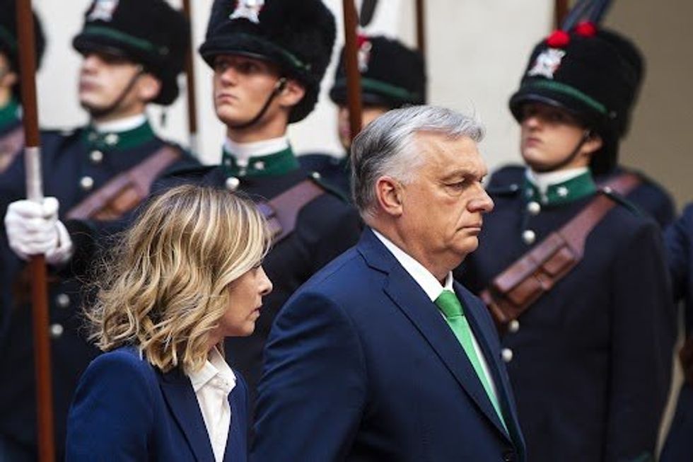 Italian Prime Minister Meloni walks besides Hungarian Prime minister Orban with slodiers lined up to their left