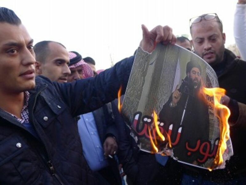 Jordanians burn a "Wanted Dead" poster of Abu Bakr al-Baghdadi, leader of ISIS