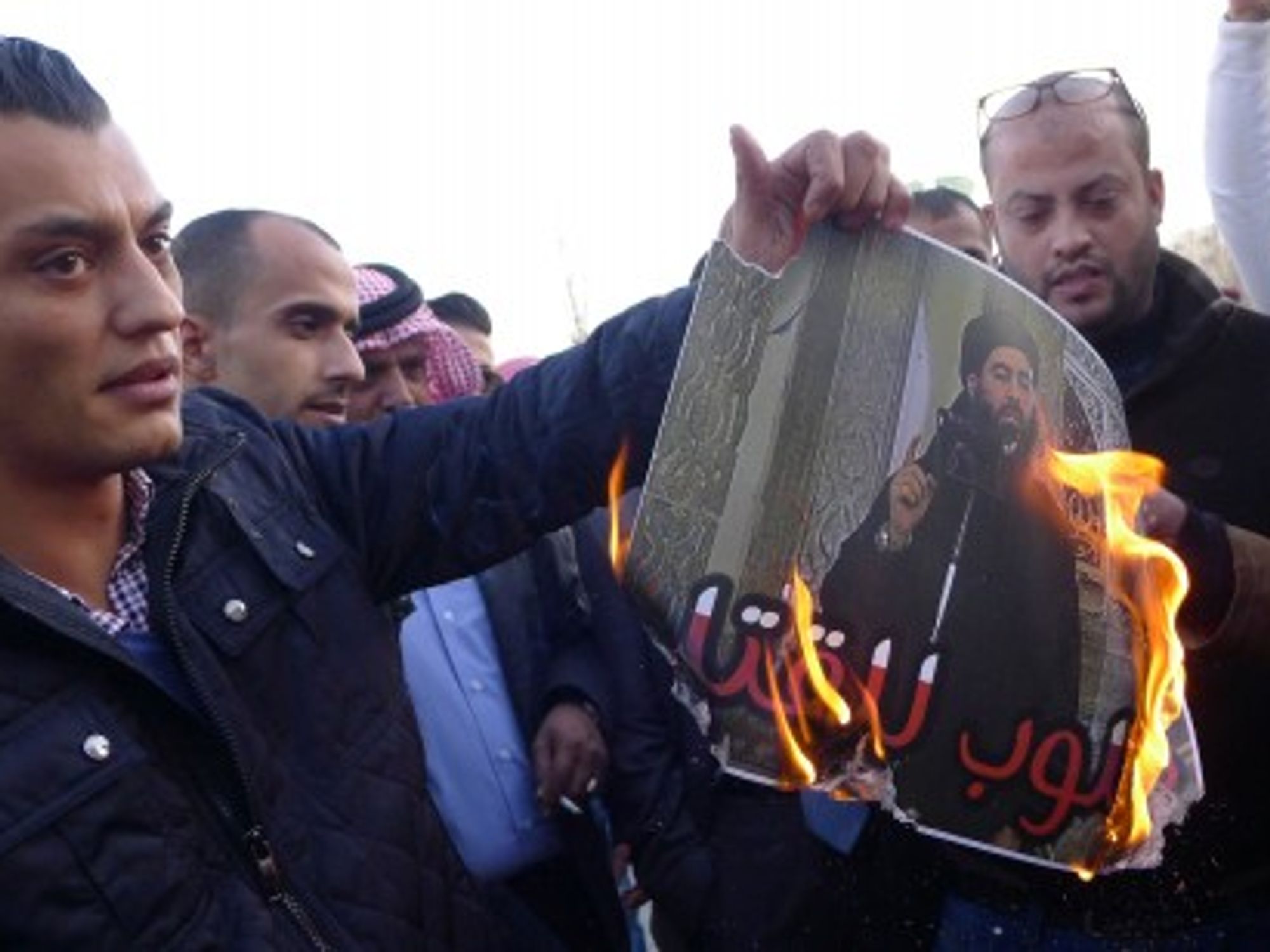 Jordanians burn a "Wanted Dead" poster of Abu Bakr al-Baghdadi, leader of ISIS