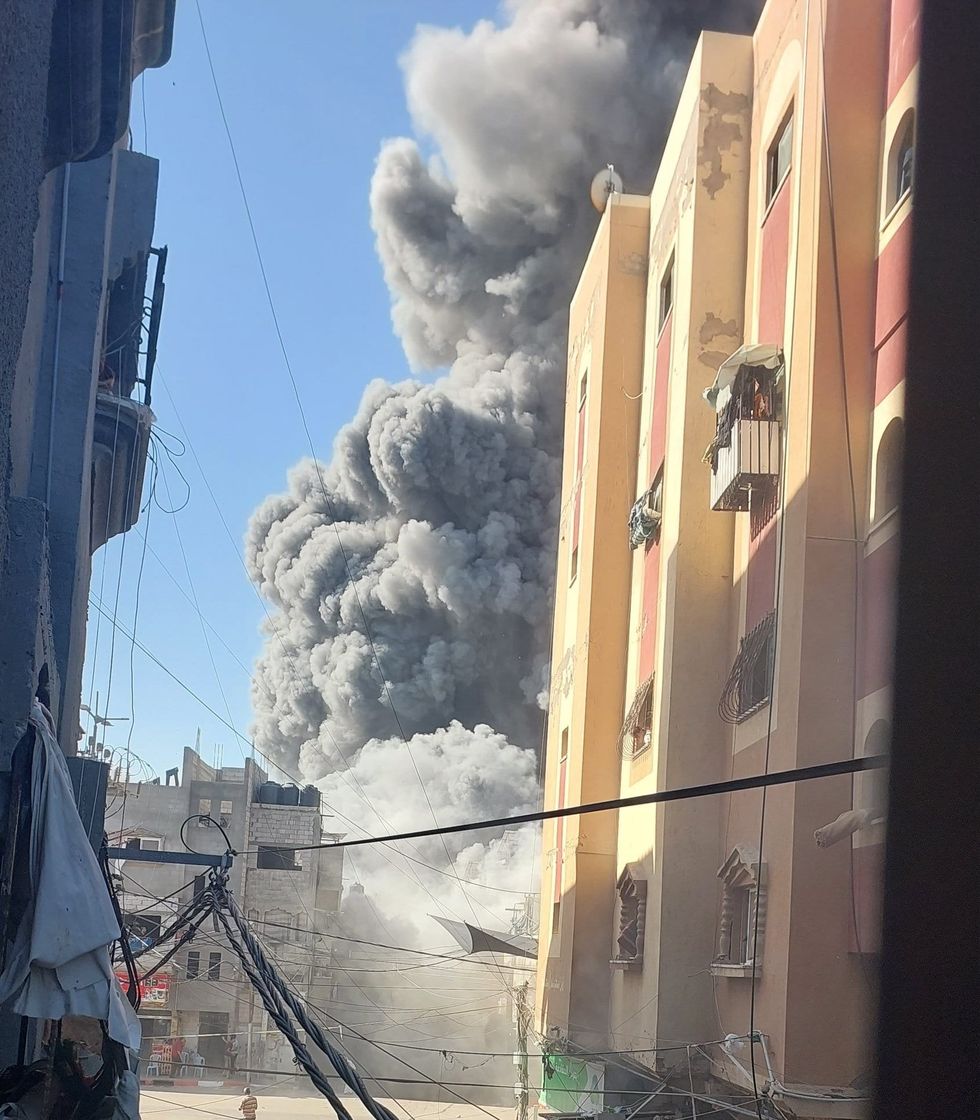Large smoke cloud rising in an area near many buildings.