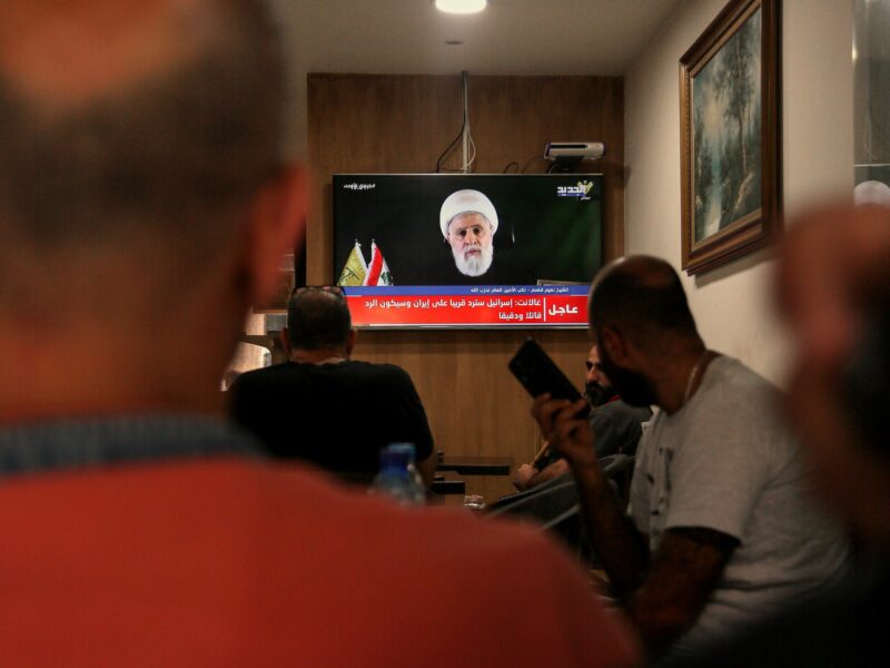 Lebanese citizens in a café in Beirut watching a televised speech by Naim Qassem.