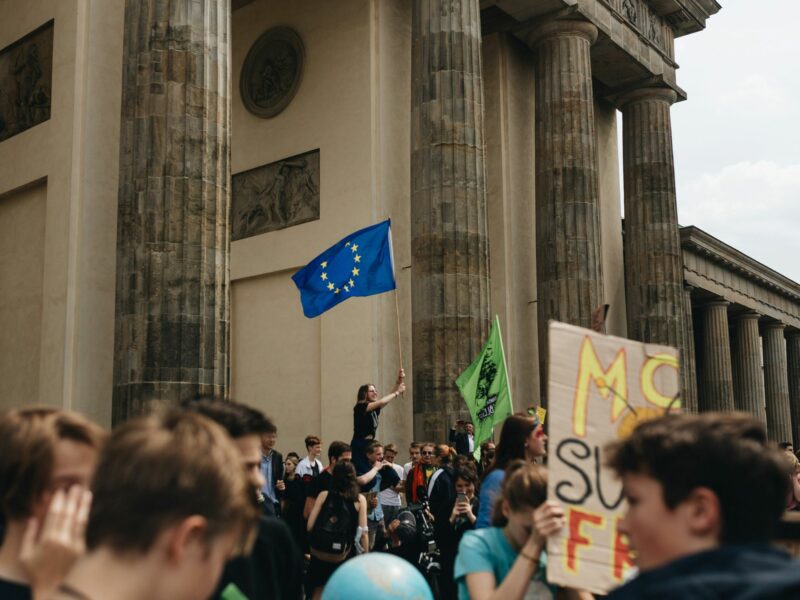 Man at the steps of a government building waving a European union flag.