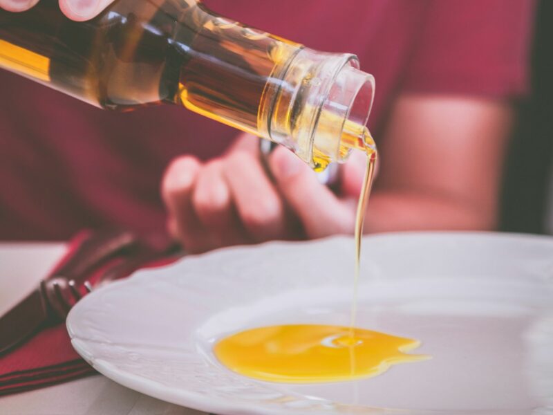 Man holding a clear glass bottle of olive oil.