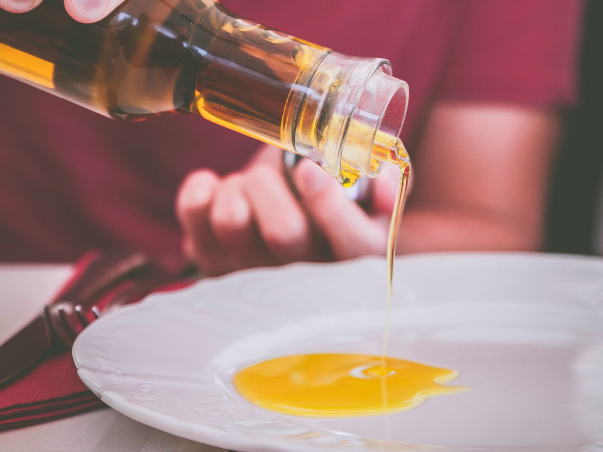 Man holding a clear glass bottle of olive oil.