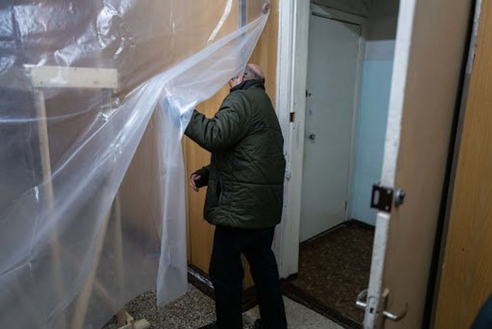 Man holding plastic sheeting to trap warm air.