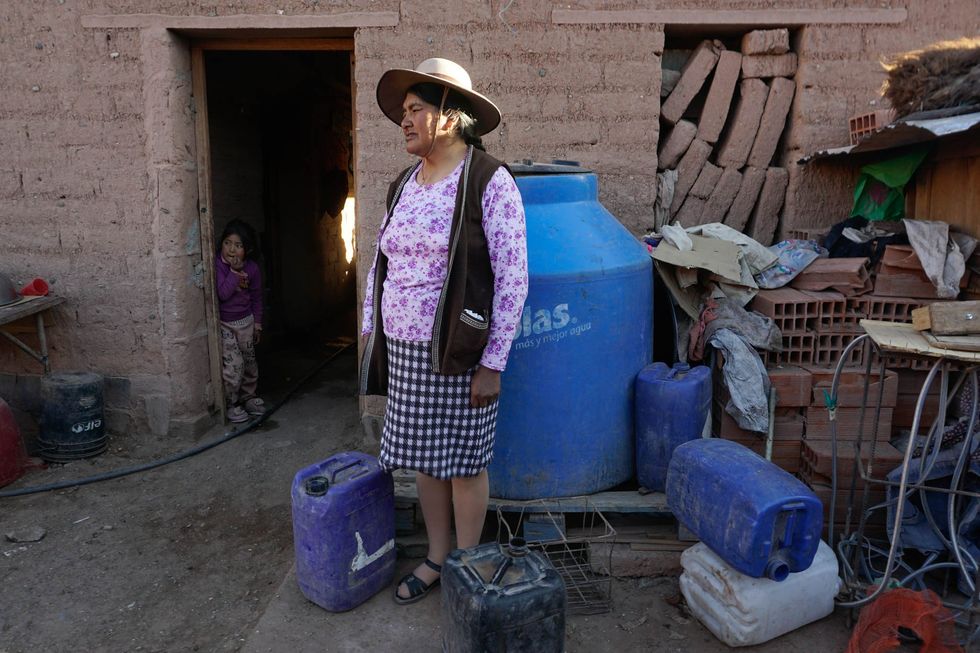 María Norma Vasquez poses for a portrait next to her water storage containers.