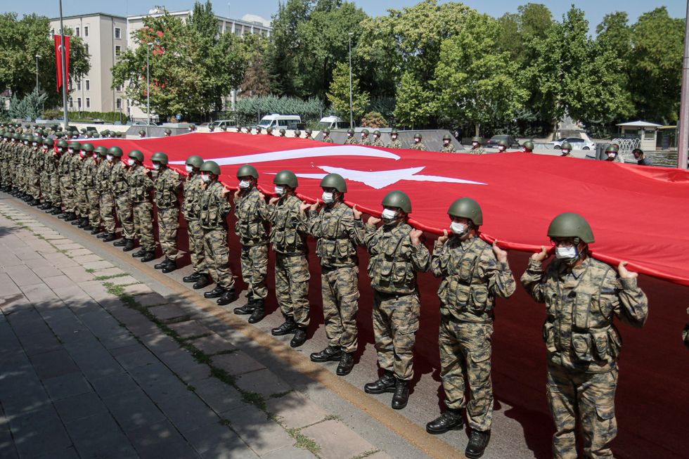 Masked Turkish soldiers in military outfit holding the Turkish flag during Victory Day​ military parade