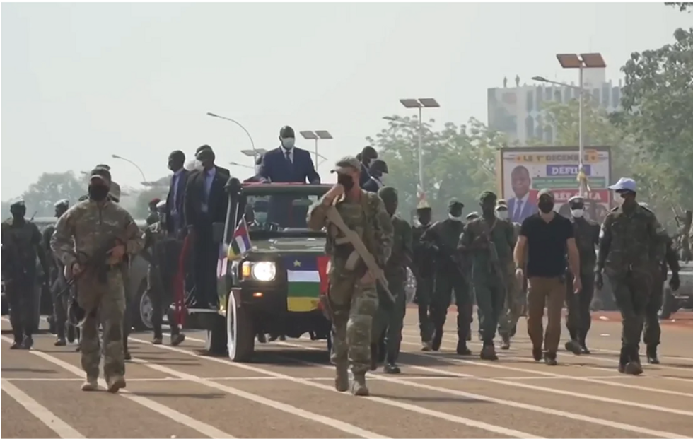 Masked Wagner mercenaries on foot surround a presidential convoy in the Central African Republic.
