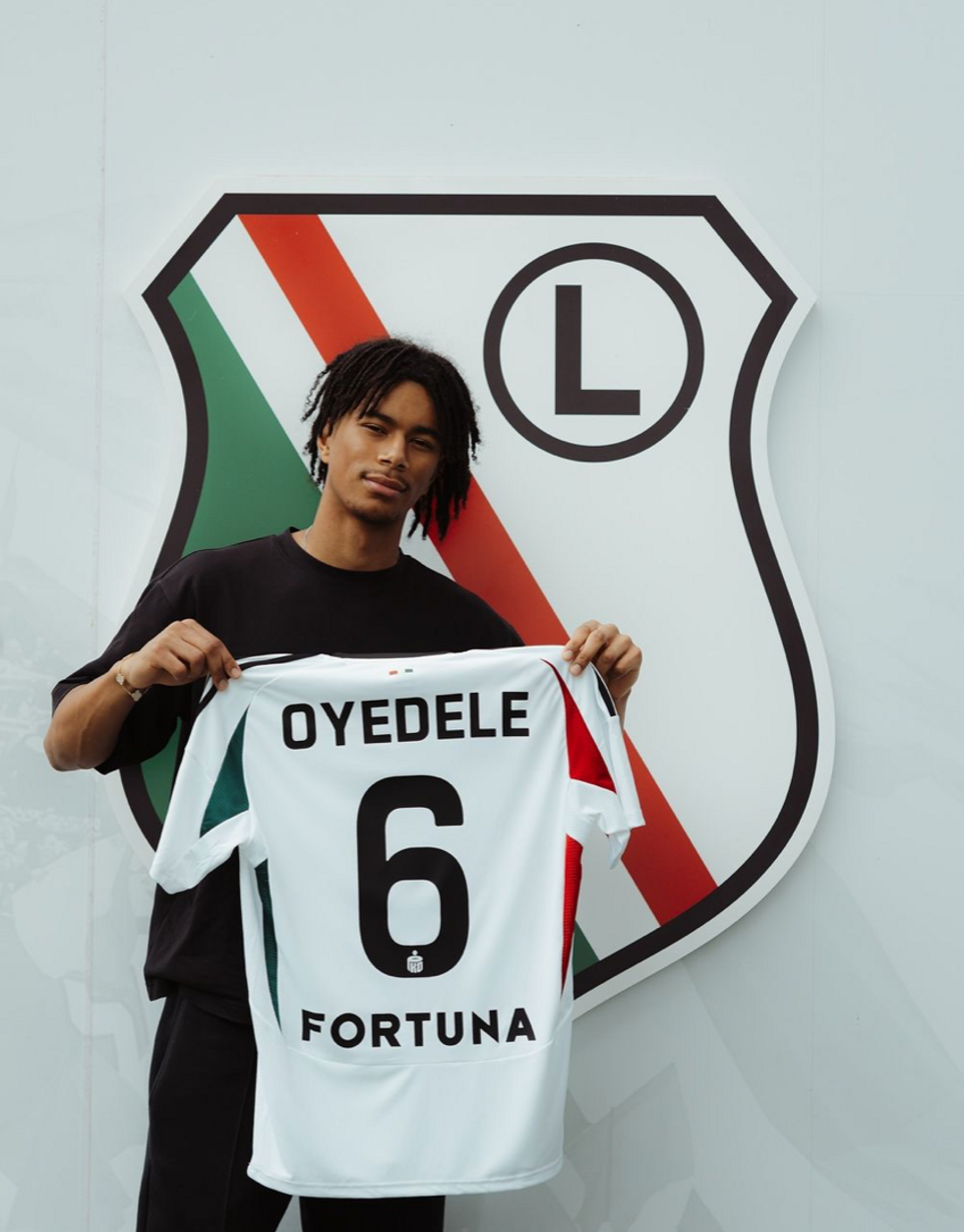 Maximillian Oyedele holding his jersey of the Legia Warszawa.