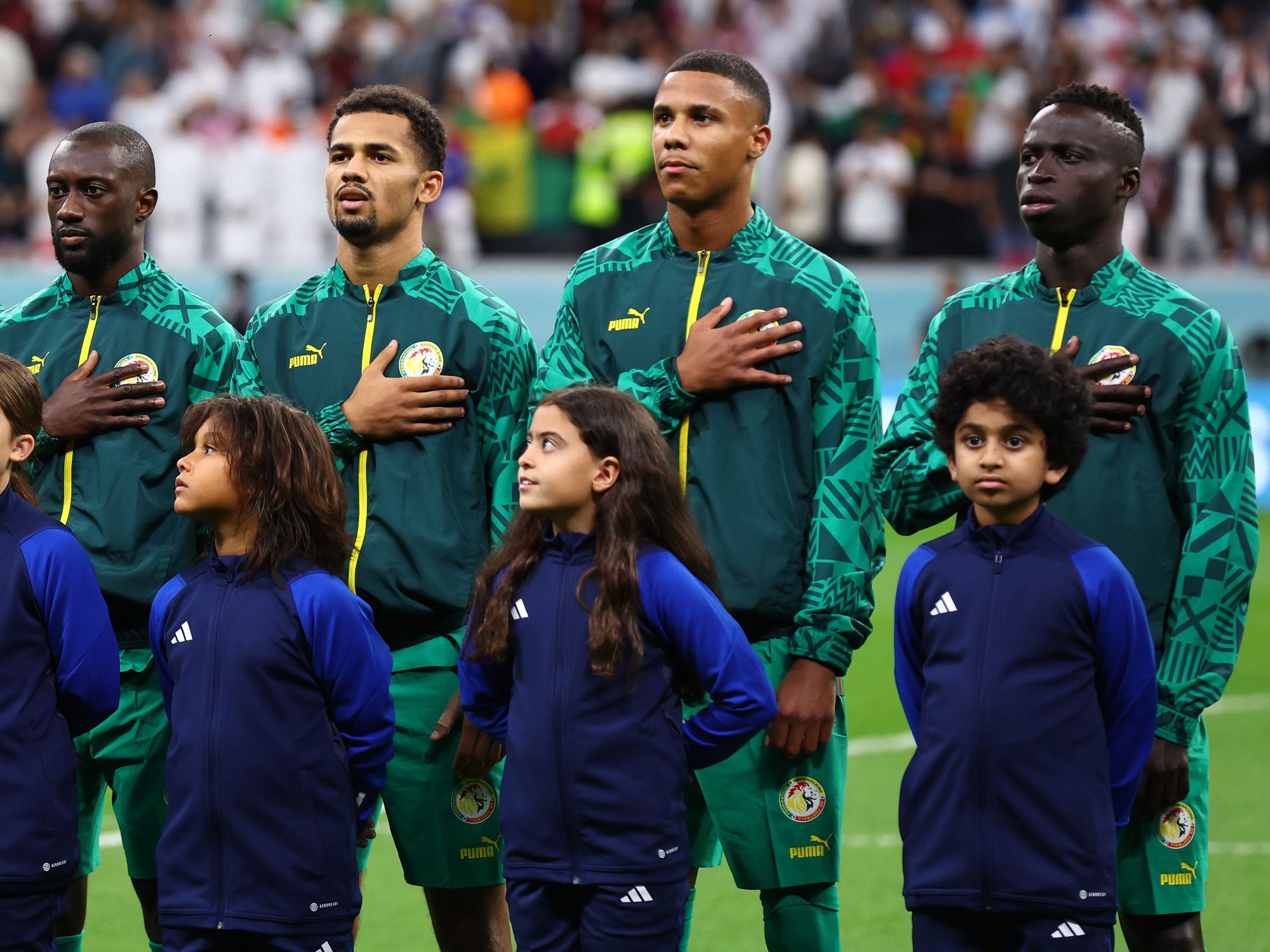 Members of the Senegal football team sing their national anthem with hands over their hearts