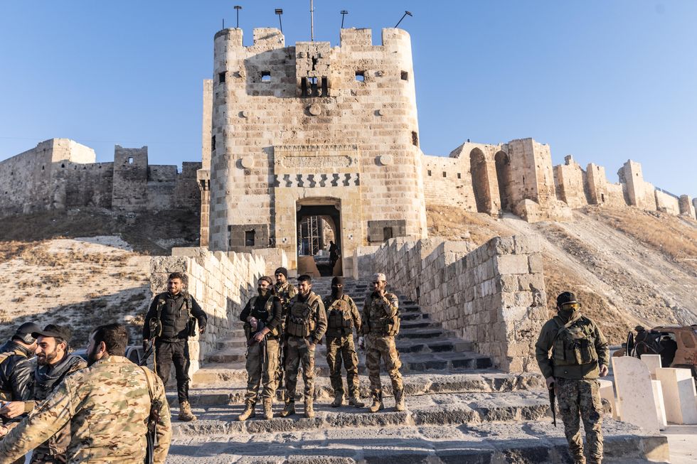 Members of the Syrian armed opposition forces stand in front of the Ancient Castle of Aleppo after seizing control of most parts of Syria's second largest city