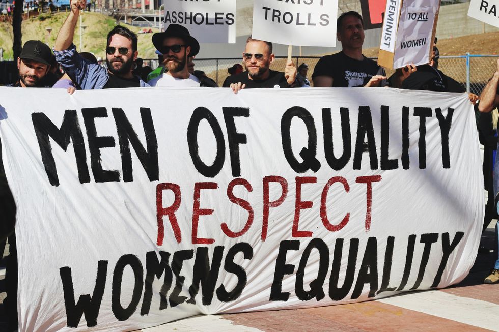 Men holding white, black and red Quality men respect the banner of women's equality on the road.