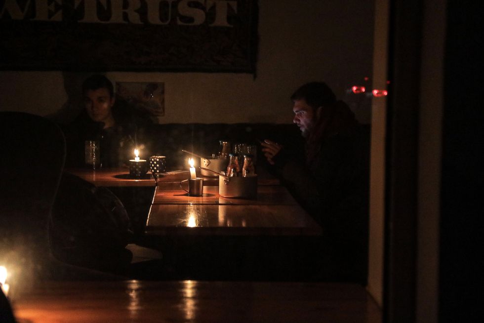 Men sit at the tables by candles in a cafe as a blackout is in place in Odesa, southern Ukraine.
