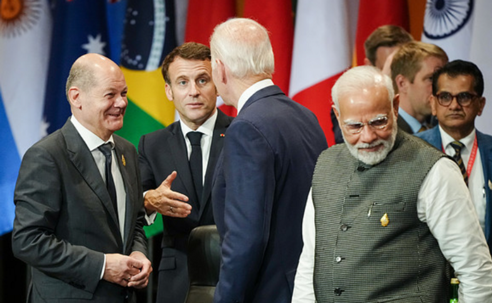 Men talking in front of various flags.