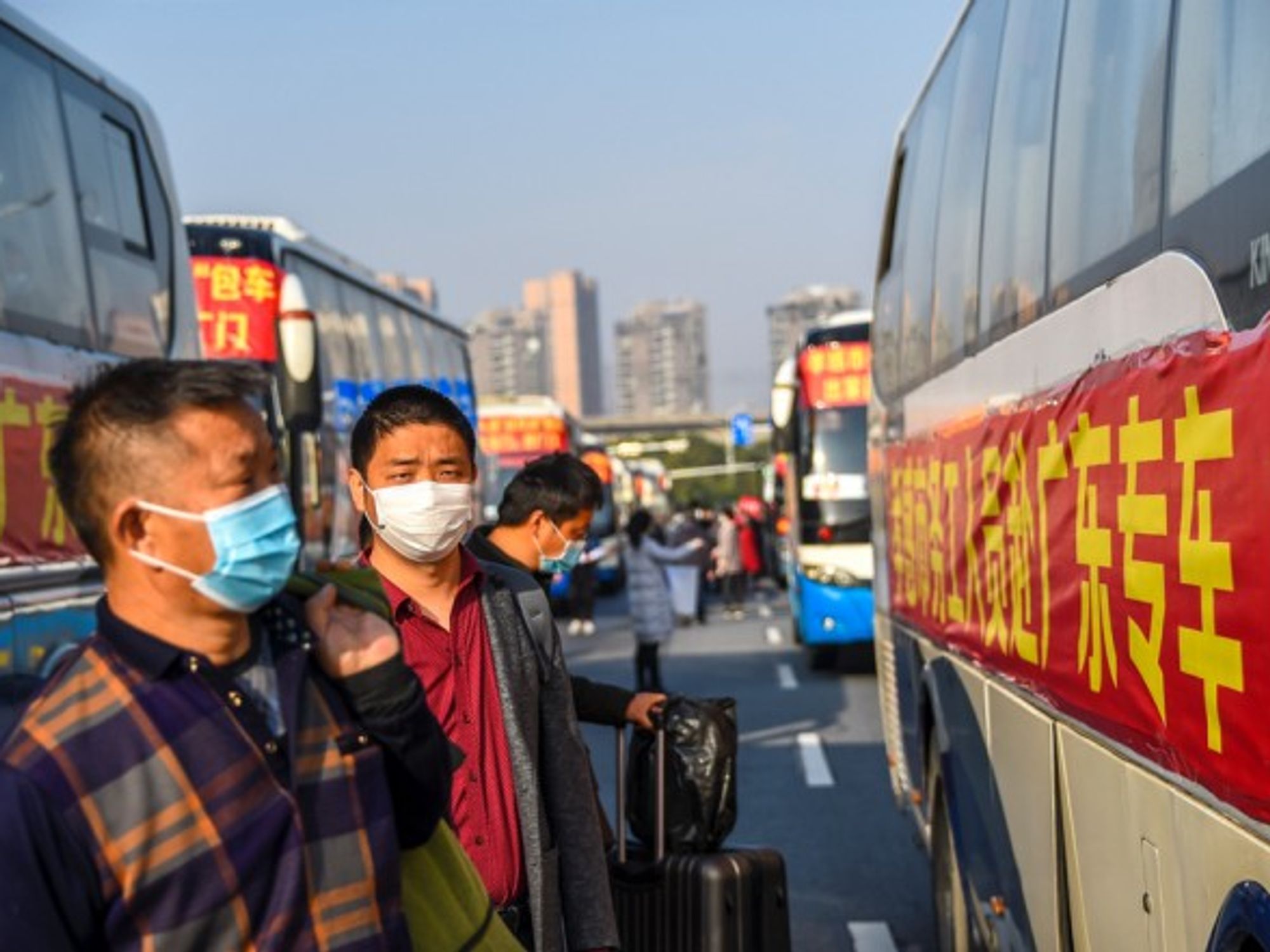 Migrant workers line up to board a chartered bus in Xiaogan