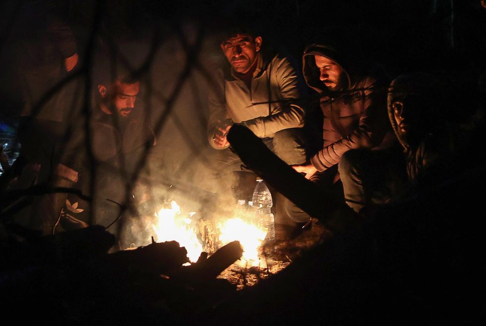 Migrants sit by the fire in a tent camp on the Belarusian-Polish border, November 2021