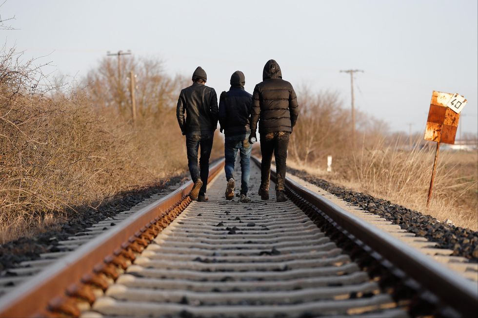 Migrants walk on a train rail near the Evros River in Greece