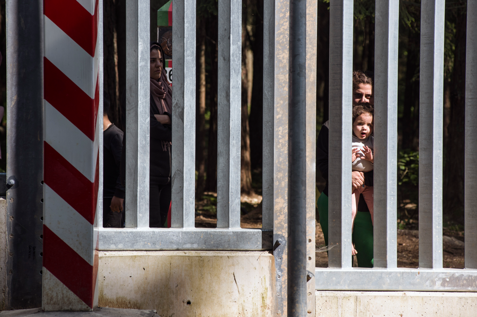 Migrants with children seeking asylum are seen at the Belarusian side of the Polish border wall in Bialowieza