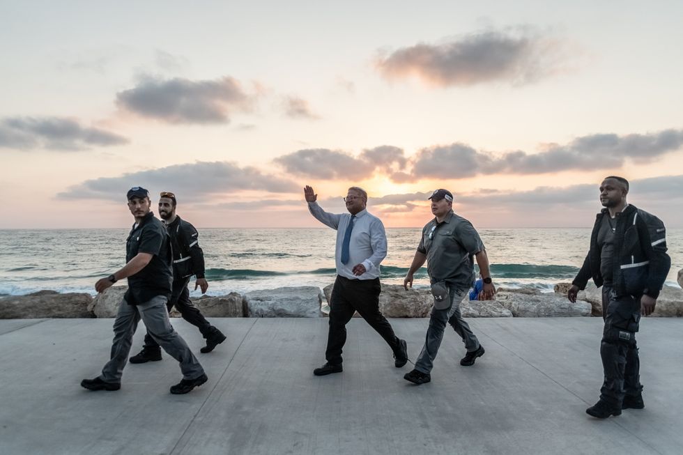 Minister Itamar Ben-Gvir walks escorted by local police, among local citizens and tourists on the Tel Aviv seafront.
