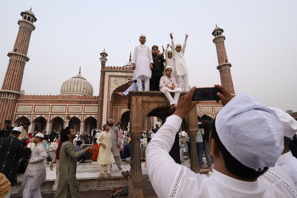 Muslim children pose for photos after offering Eid al-Fitr special prayers at Jama Masjid in the Old quarters.