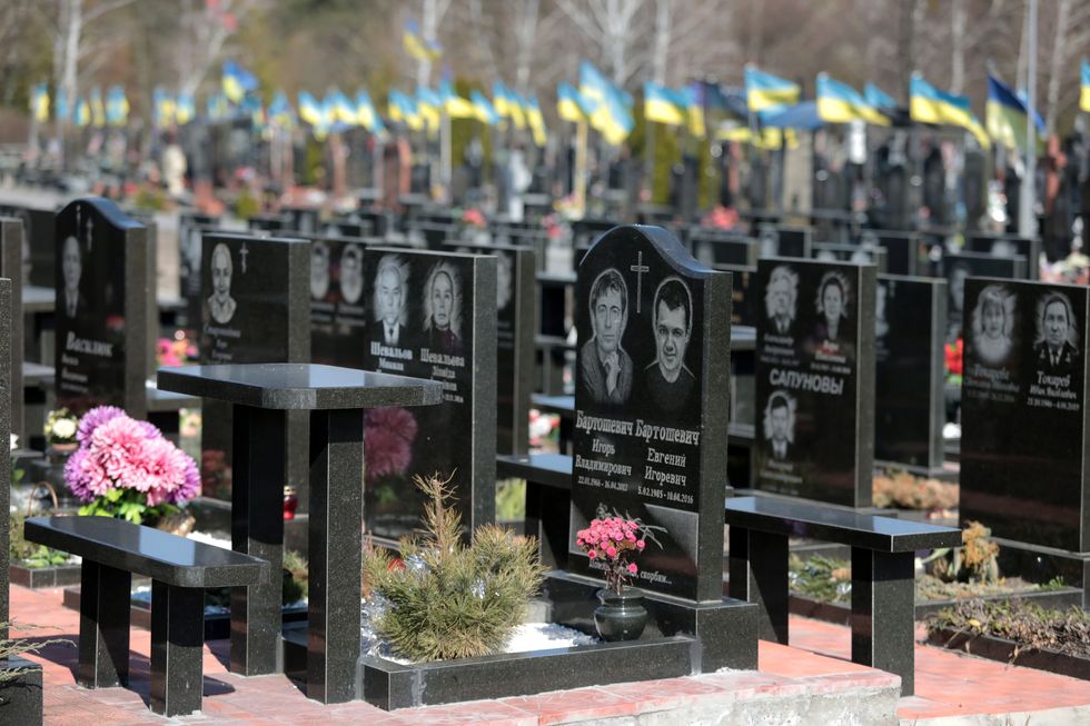 National flags of Ukraine wave over the tombs of soldiers at the Troieshchyna cemetery in Kyiv