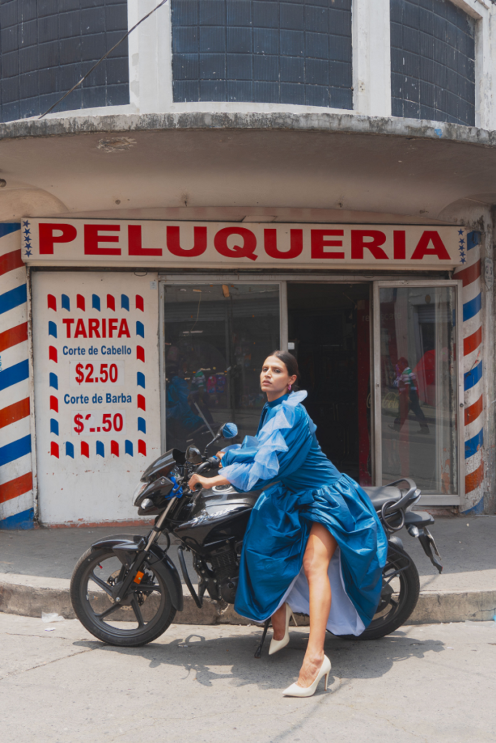 Nessa Sosa posing on a motorcycle in a blue dress.