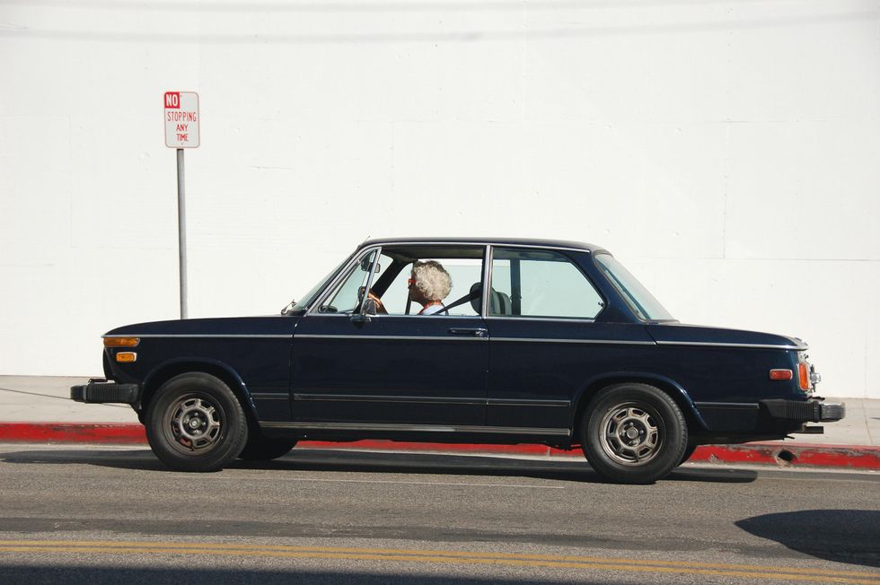 Old woman driving blue car