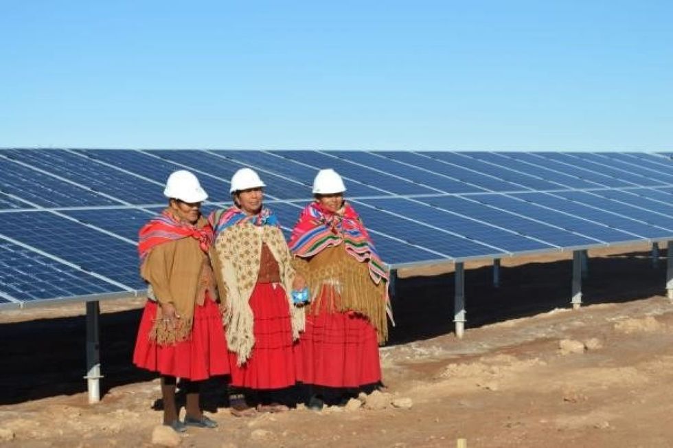 Oruro solar plant workers standing with solar panels.