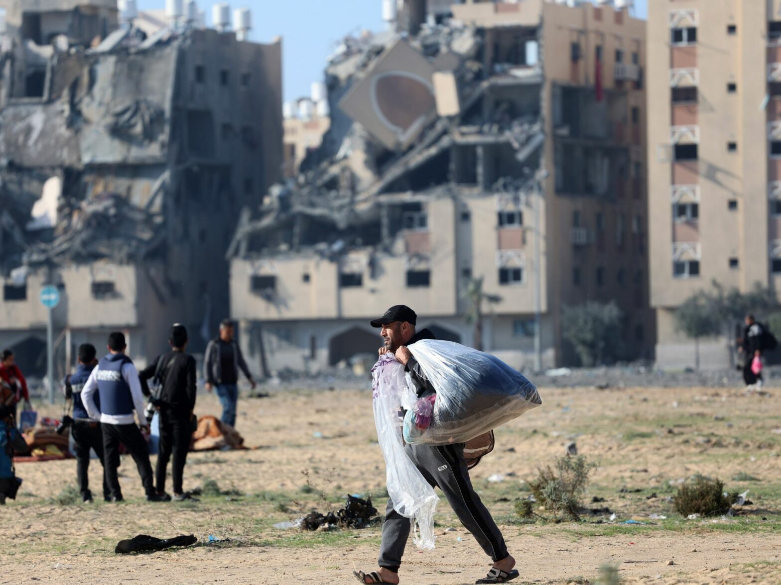 Palestinian man walks in front of the destroyed buildings as they flee their homes after an Israeli strike hit 7 towers in the city of Hamad.