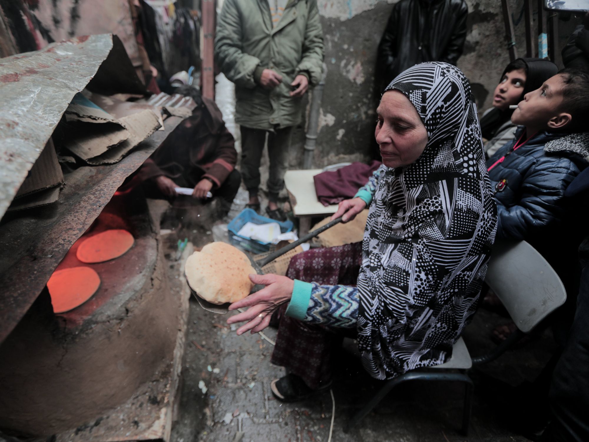Palestinian woman makes bread in an old oven in the Al-Maghazi refugee camp in the central Gaza Strip.