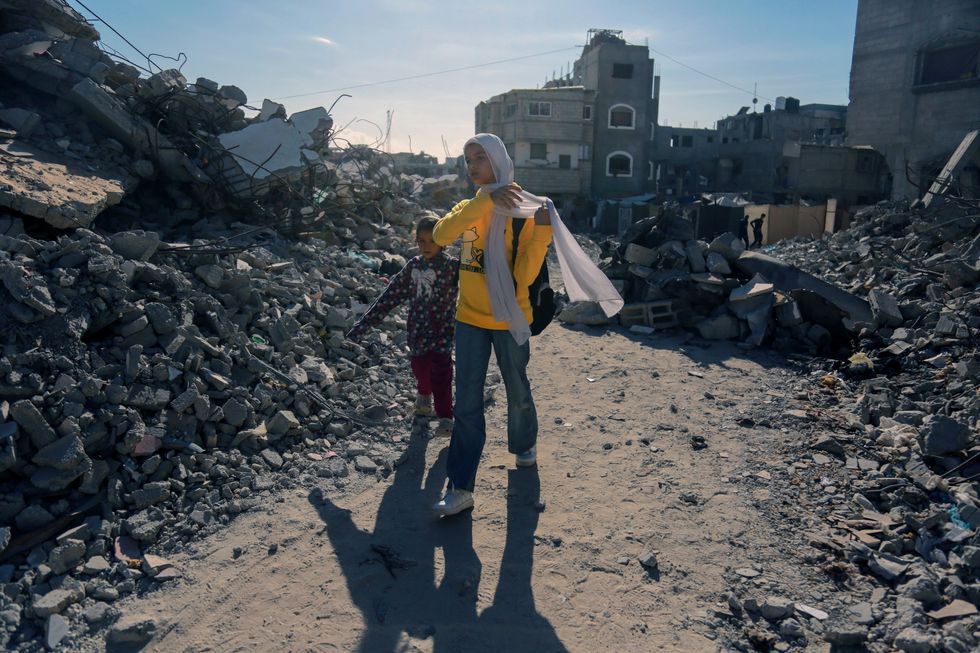 Palestinian youths walk amongst the rubble of destroyed buildings in Khan Younis.