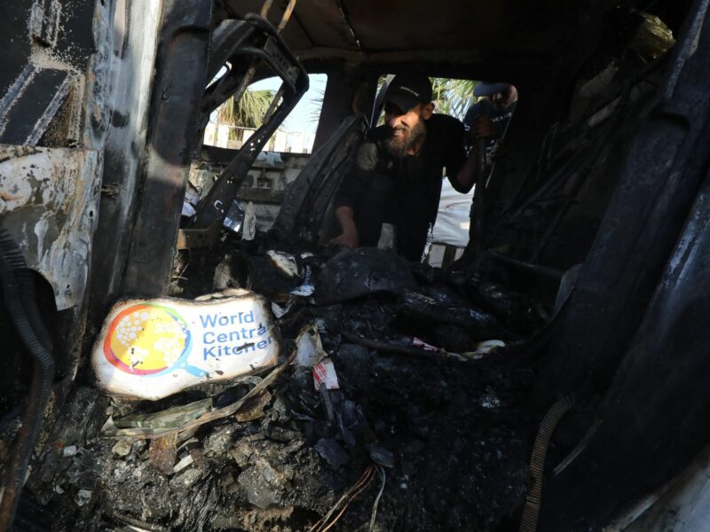 Palestinians inspect vehicles damaged by Israeli attacks.