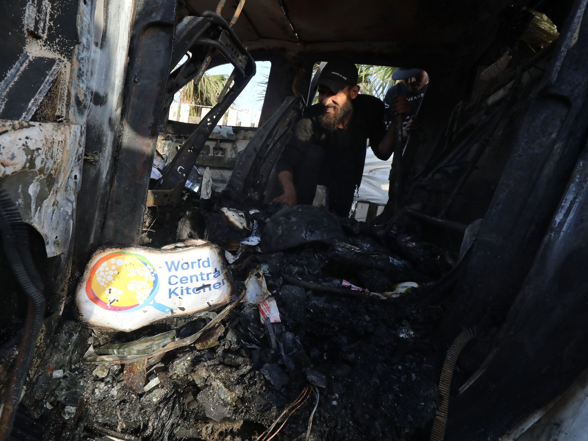Palestinians inspect vehicles damaged by Israeli attacks.