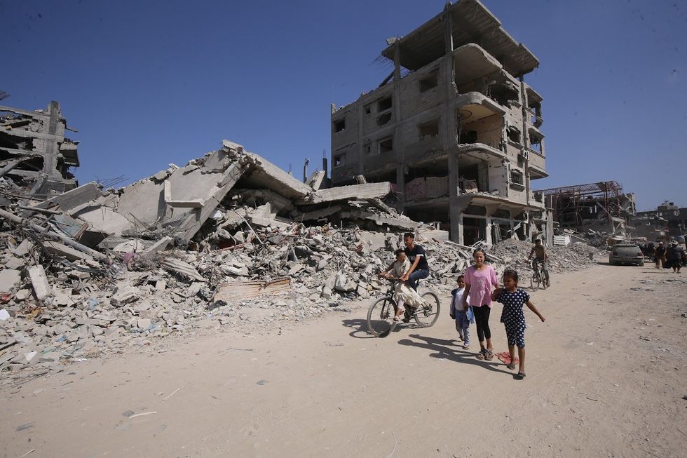 Palestinians walk past rubbles of houses in Khan Younis.