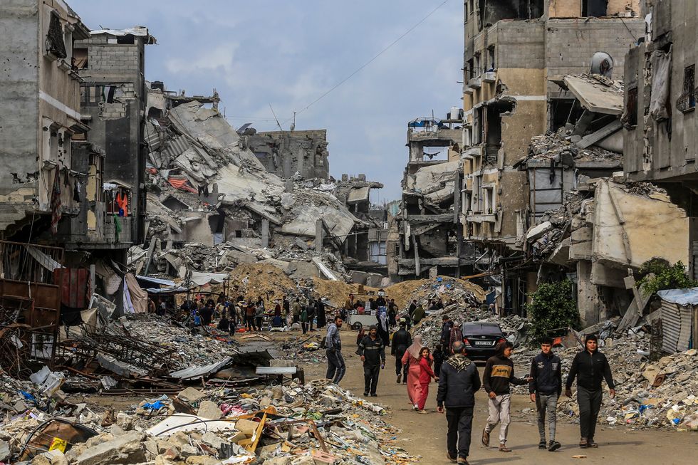 Palestinians walk through the rubble in Khan Younis, after Israeli forces withdrew as part of the ceasefire argument.