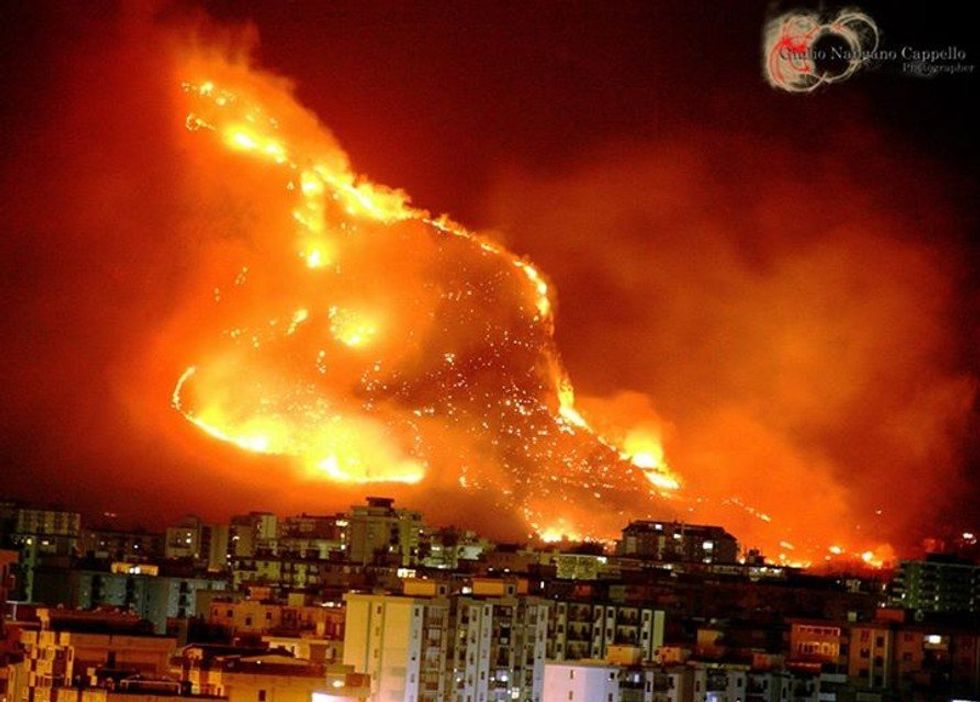 Parma cityscape, with fire raging on a mountain slope in the background