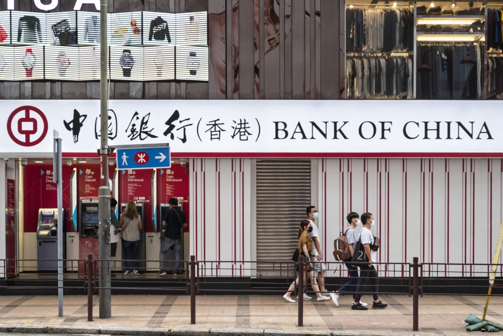 Pedestrians walk past the Chinese state-owned commercial banking company Bank of China branch in Hong Kong.