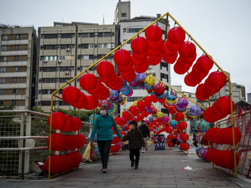 Pedestrians walk under a vibrant archway of red lanterns on a bridge in Taipei, Taiwan ushering in the Year of the Dragon