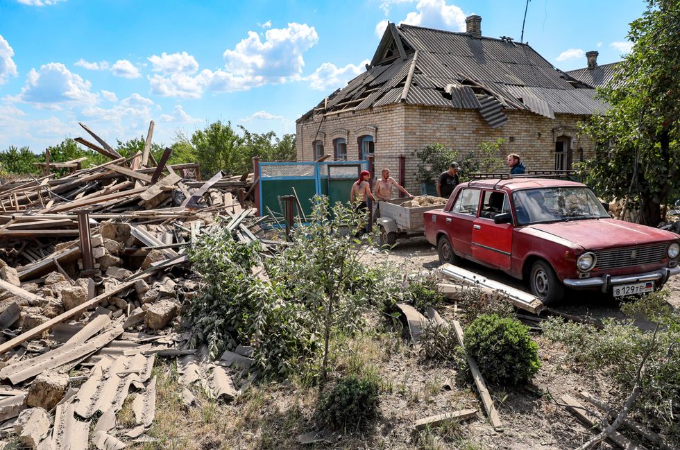 People are seen by a residential house damaged after a military strike by the Armed Forces of Ukraine on the rural town of Staromikhailovka.